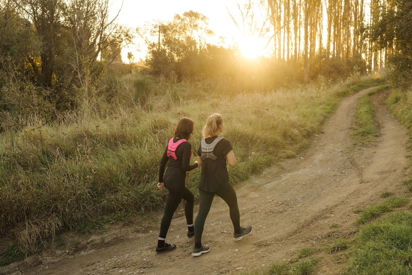 Two ladies exercising on a forest trail at sunrise