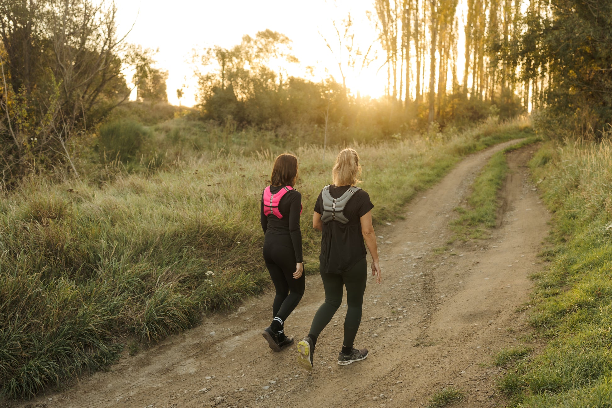 Two ladies walking a forest trail in weighted exercise vests.