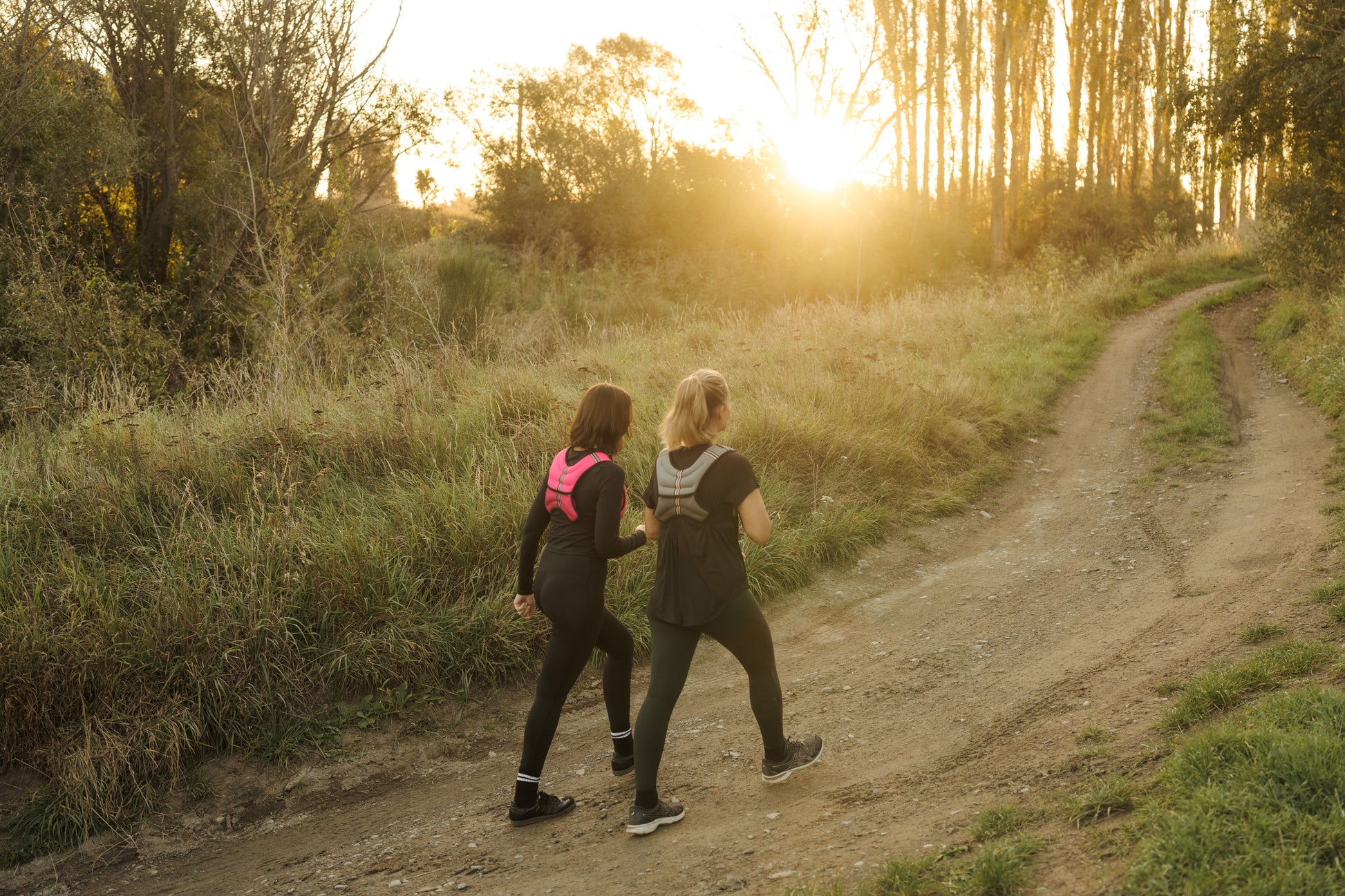 Two ladies exercising on a forest trail at sunrise